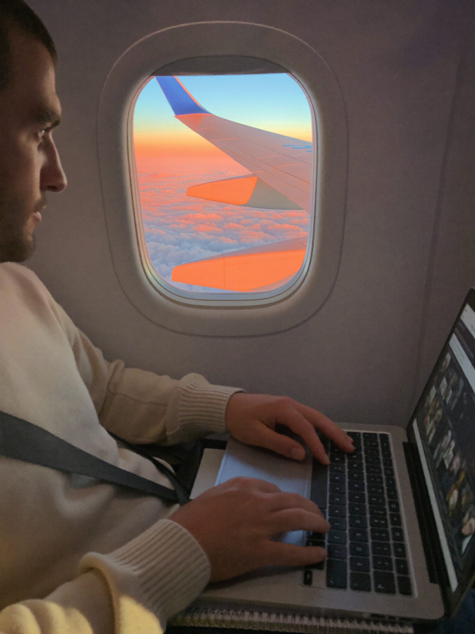 A builder working from an airplane window seat above the clouds